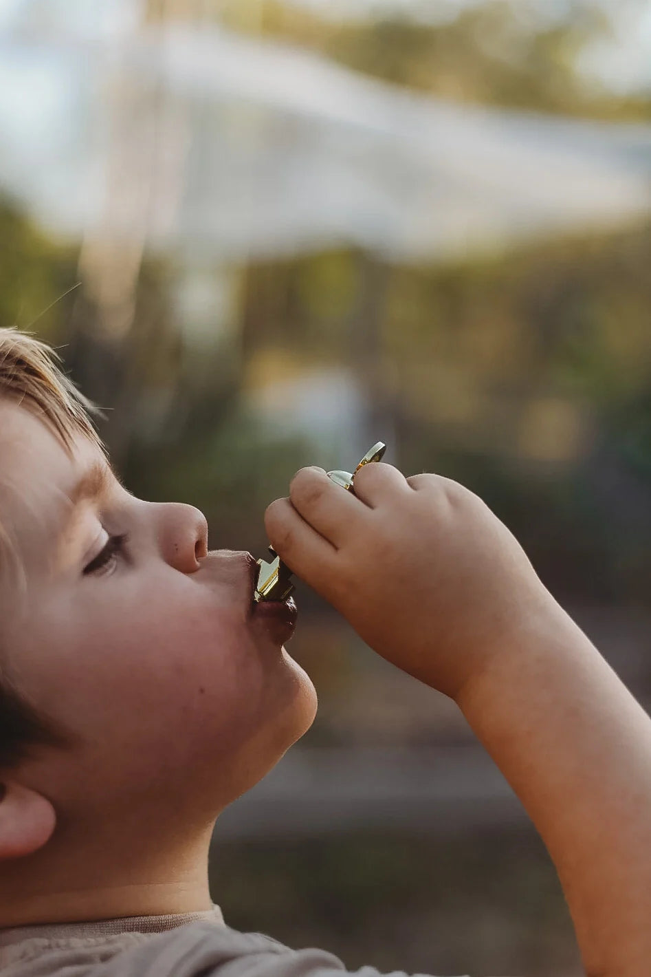 Kid taking a snack break during outdoor play — cozy camping lifestyle moment for family adventure and nature exploration.