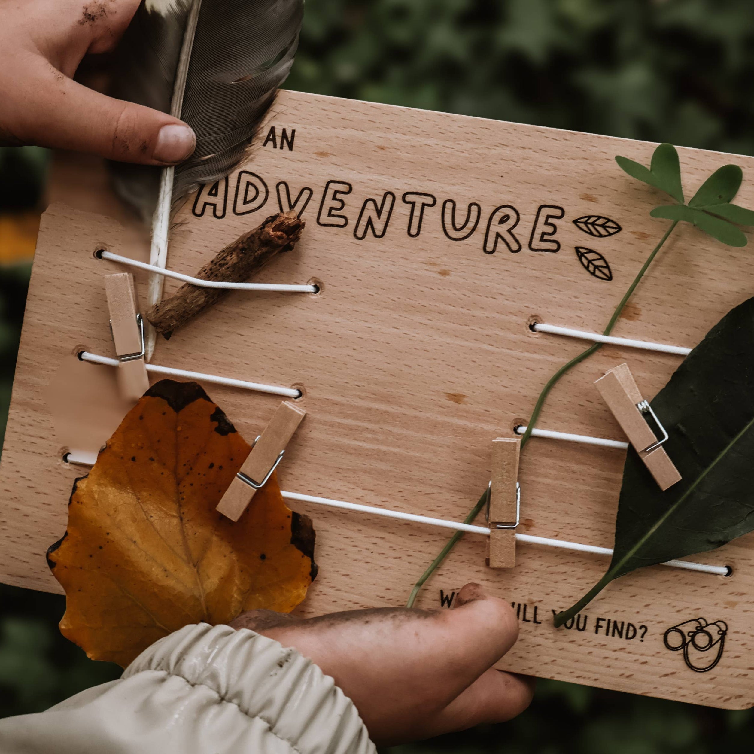 Wooden board with nature-themed decorations held by a person outdoors