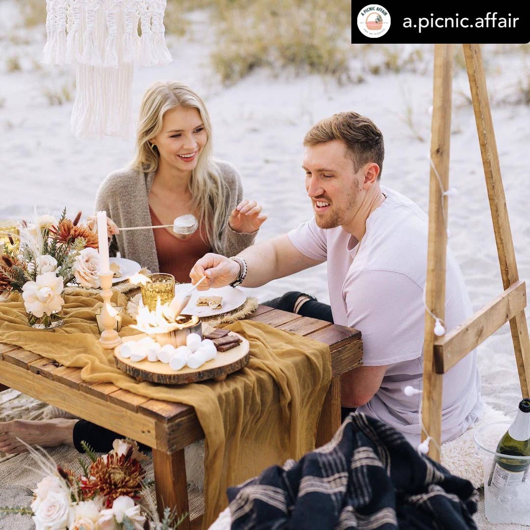 Couple enjoying a picnic outdoors with candles and flowers.