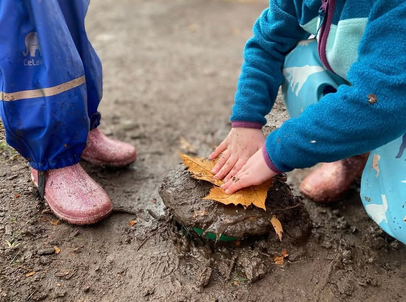 Children playing with mud and leaves on a wet day