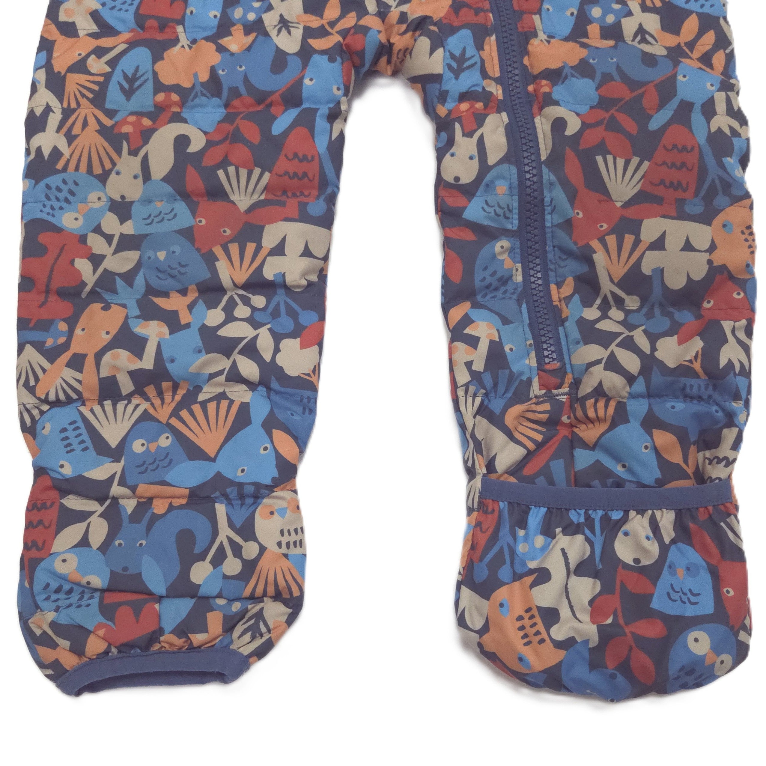 A pair of children's insulated snowsuit fold-over booties featuring a colorful, playful pattern of cartoon animals, plants, and shapes on a dark navy blue background. The pants have a front zipper and elastic cuffs.
