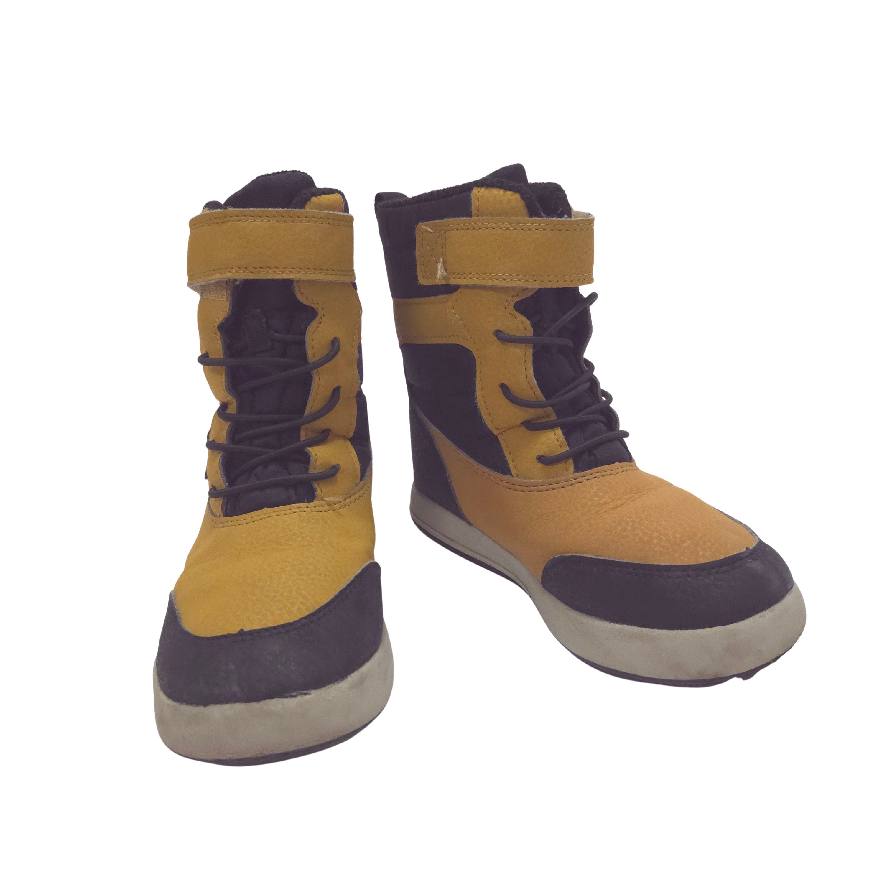 A pair of high-top winter boots in mustard yellow and black, featuring laces, hook-and-loop straps, and thick soles, shown against a plain white background.