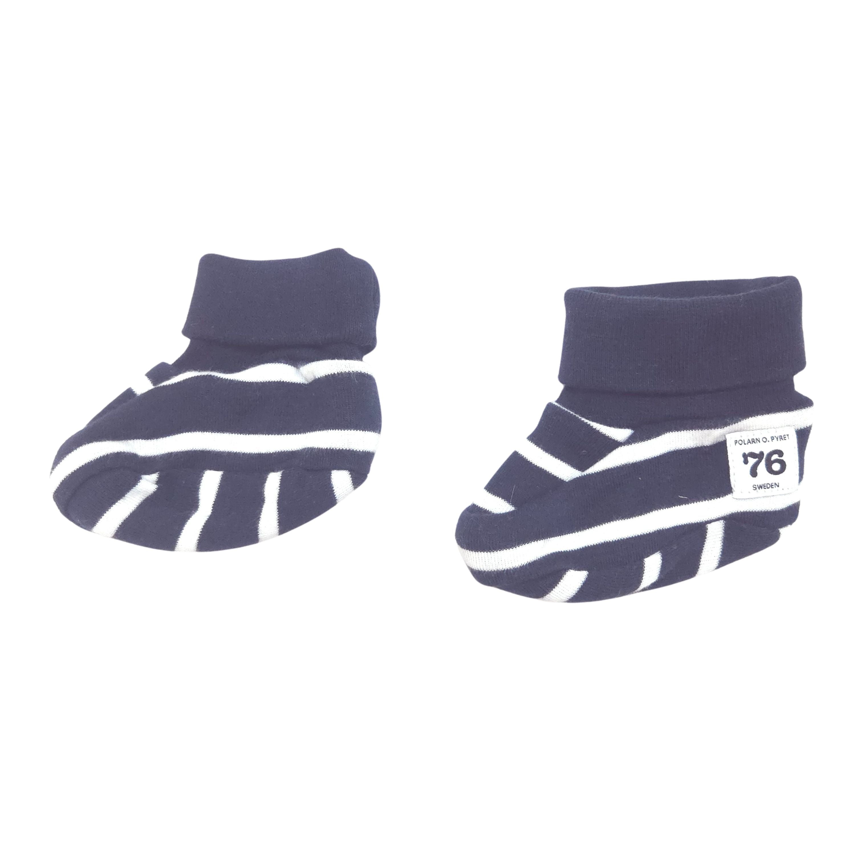 A pair of baby booties in navy blue and white stripes, and a small white brand label on the side.