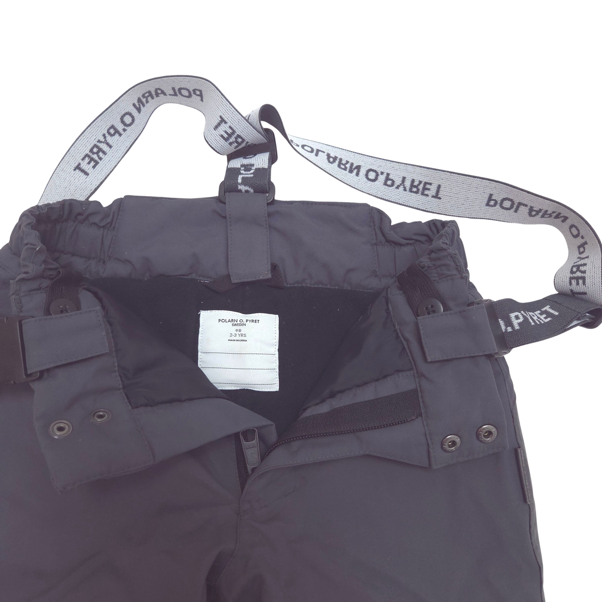 Close-up of a dark gray snow pants showing the inner waistband with elastic straps and a white brand label that reads POLAR O'PYRETT.