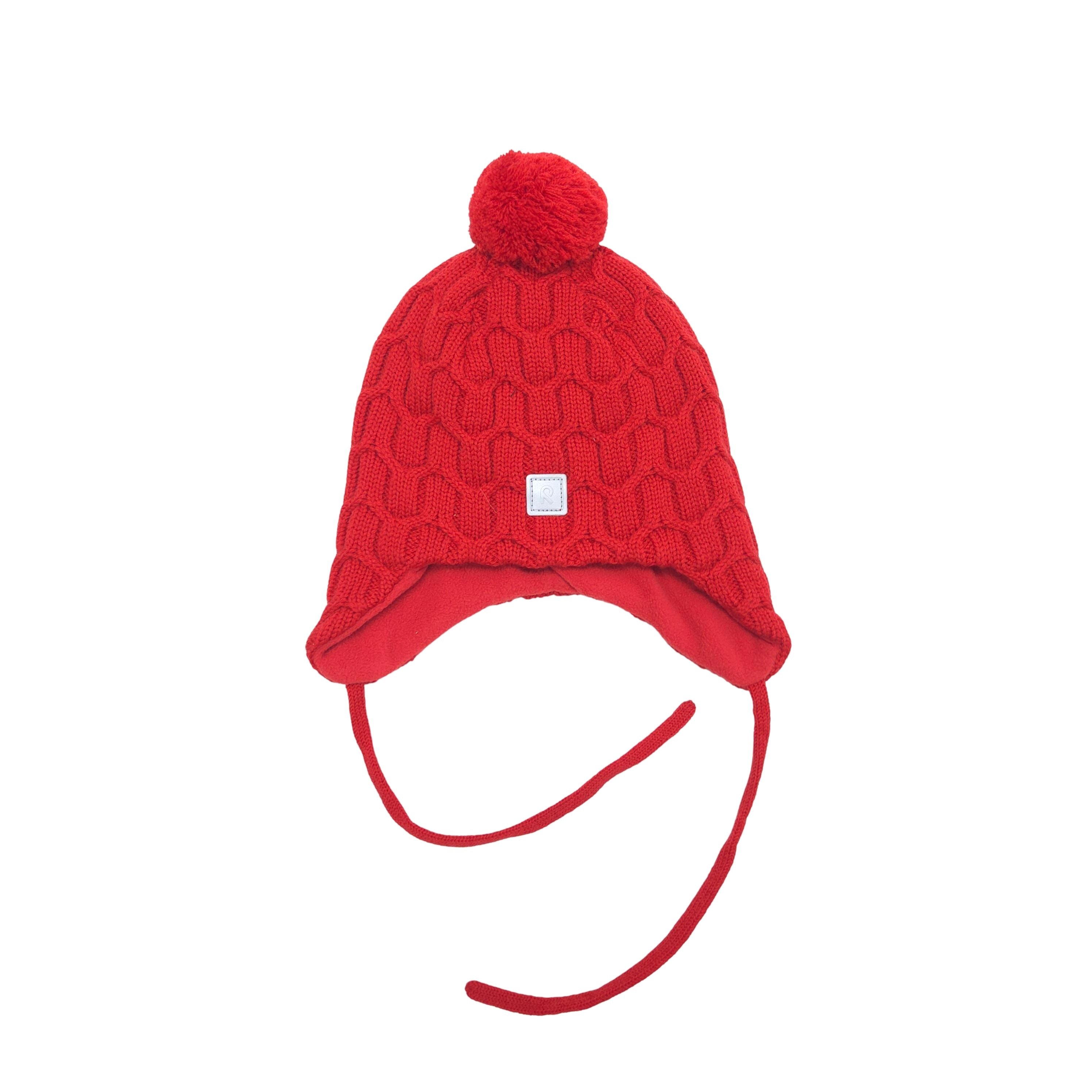 A red knit winter hat with a pom-pom on top, ear flaps, and long ties, shown against a plain white background.