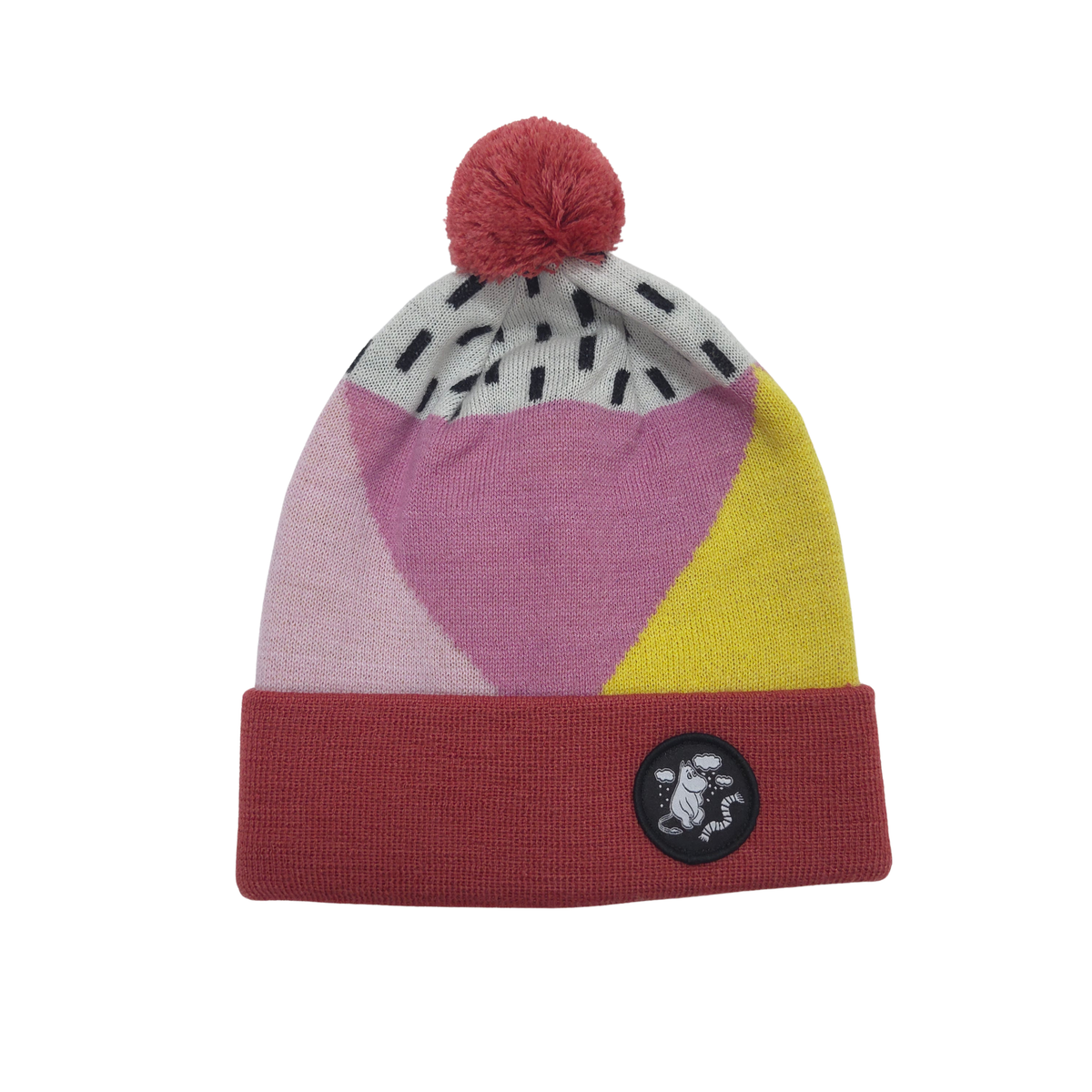 A multicolor knit beanie hat with a red pom-pom, featuring geometric color-blocked panels of pink, yellow, and light gray with black dash patterns, and a folded cuff with a circular black logo patch.