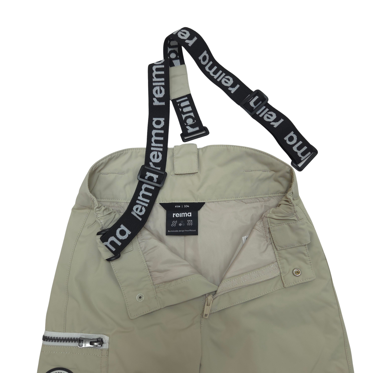 A close-up of a light beige shell pants with a black adjustable strap featuring the white 'reima' brand logo, displayed against a solid white background.