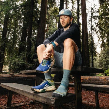 Adult in a blue rain jacket with a hood on and a apple logo 