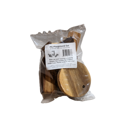 A packaged wooden playground set in a clear plastic bag with a white label reading 'PG Playground Set'. The set includes natural wood pieces such as a round platform and smaller components visible through the packaging.