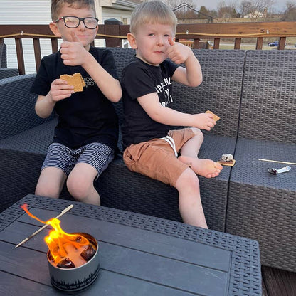 Two children sitting on a patio with a small fire pit in front of them.