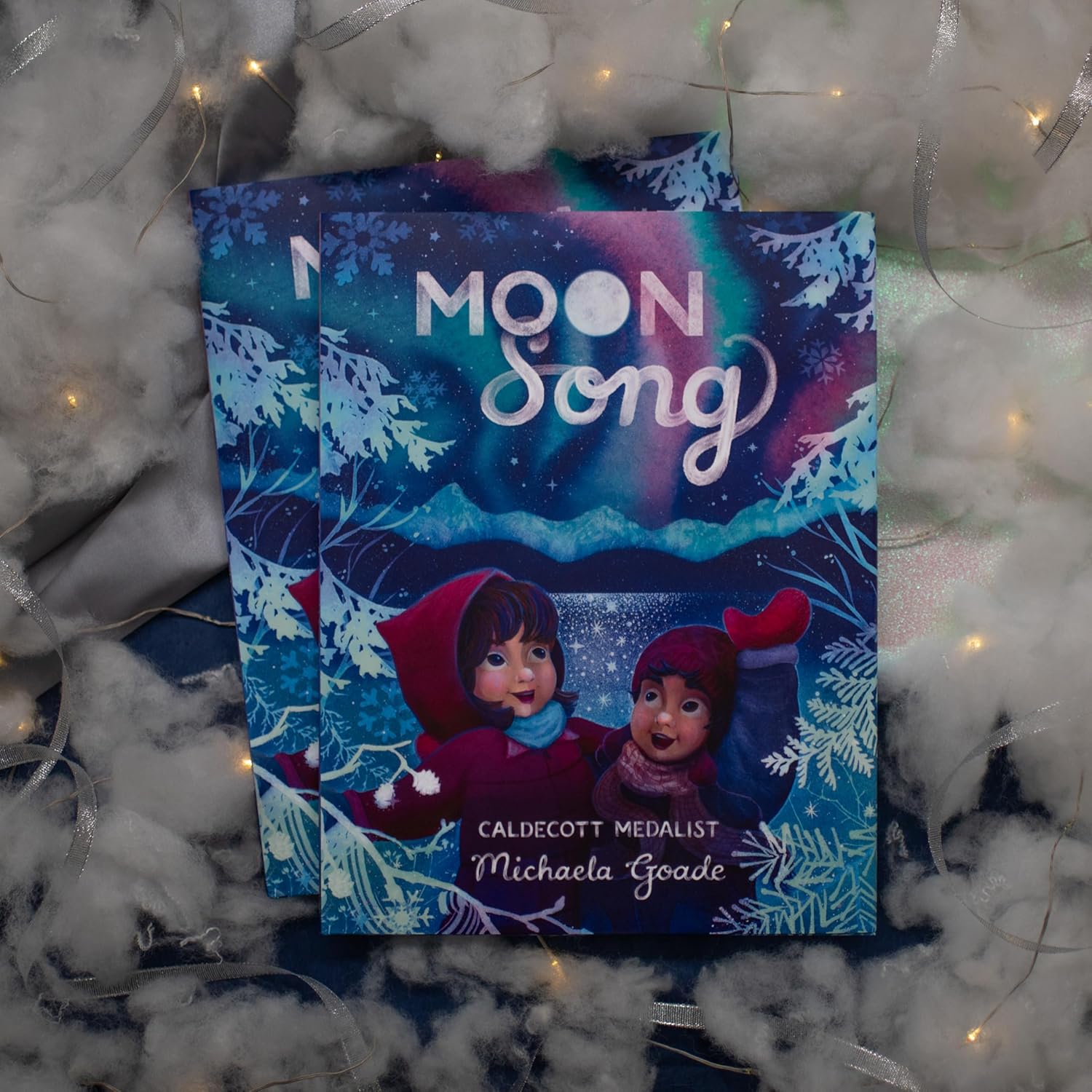 Book titled 'Moon Song' by Michaela Goade on a snowy background