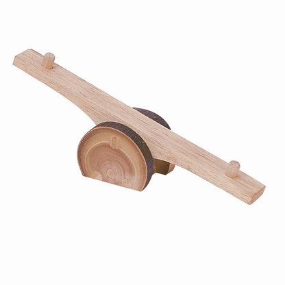 A wooden seesaw toy with a natural light wood plank, a round log base, and small pegs for support, shown on a plain white background.