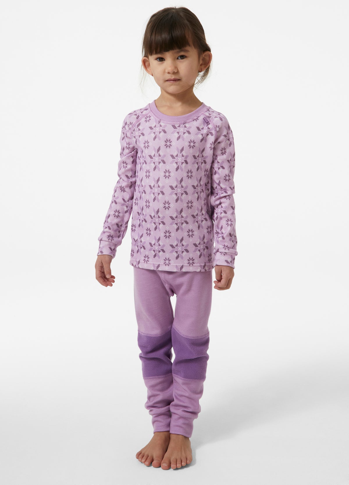 Child wearing a purple pajama set with a floral pattern on a white background