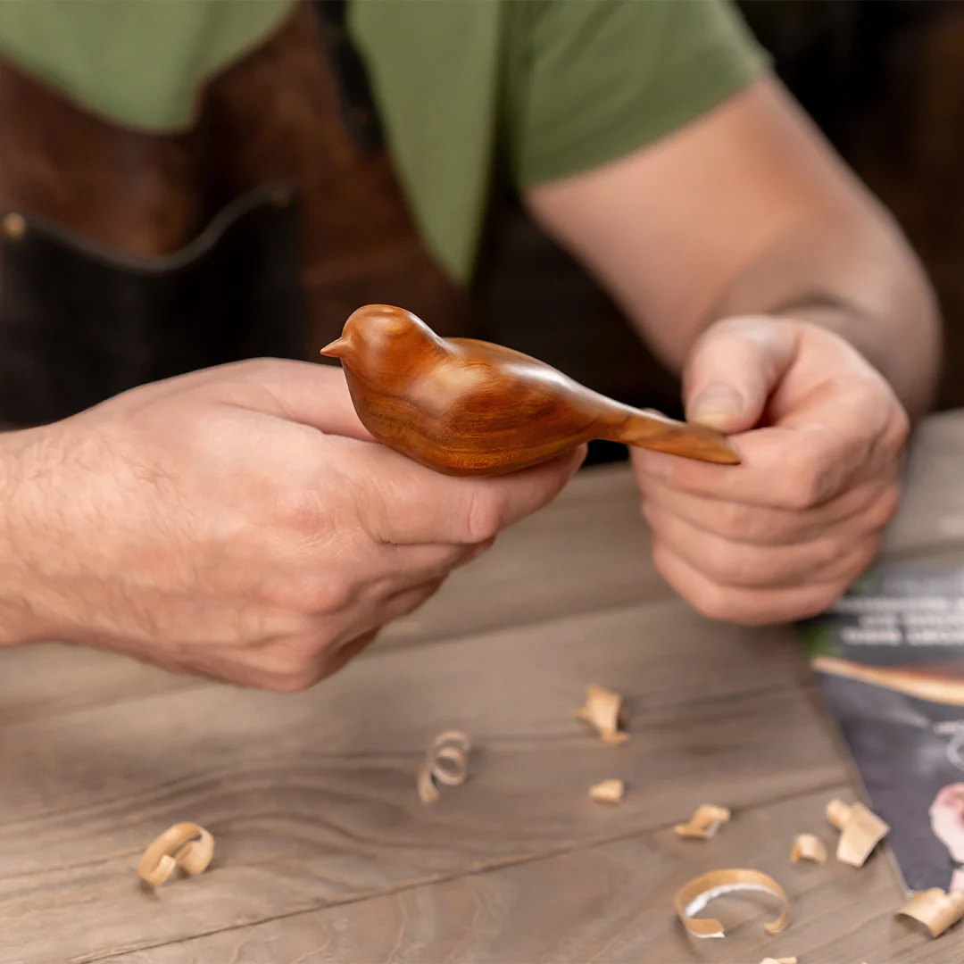 Person holding finished wooden bird from 
carving kit