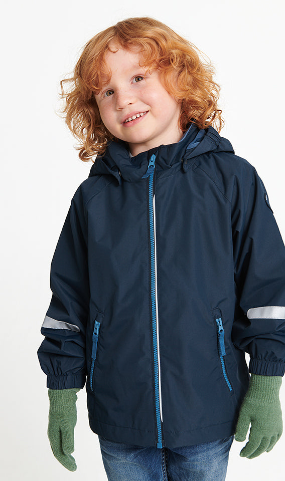 Child with curly red hair wearing a navy blue hooded rain jacket with light blue zipper details, green gloves, and blue jeans, photographed against a clean white background.
