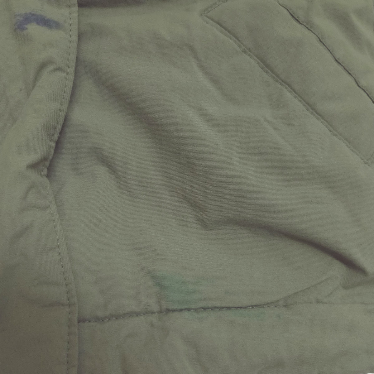 An olive green hooded puffer jacket showing stain