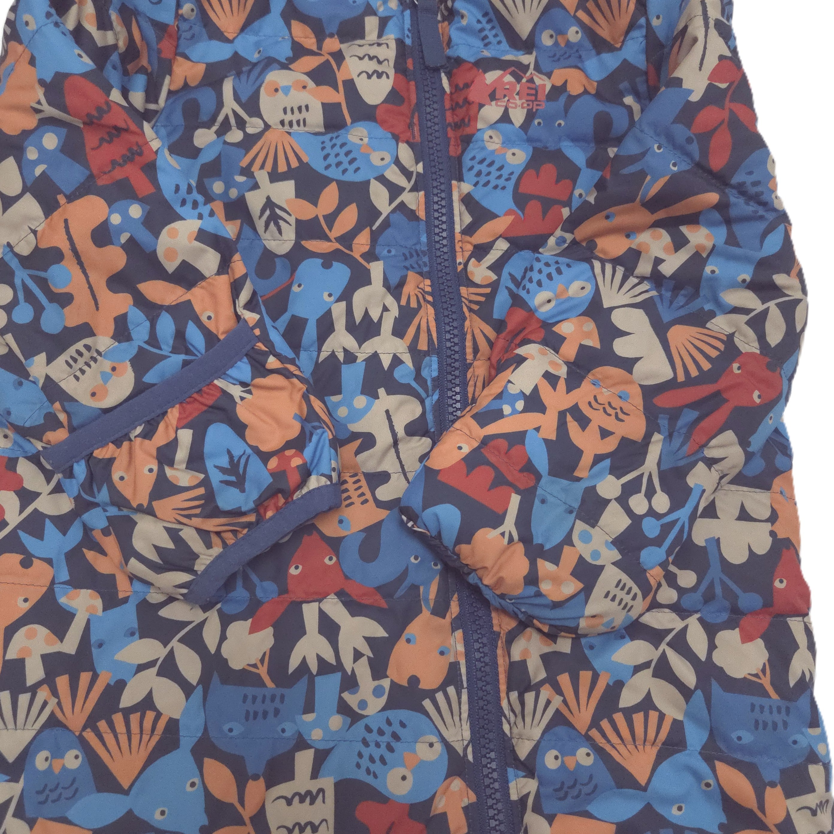 A close-up of a children's puffer suit fold-over mitts featuring a colorful, playful pattern of cartoon owls, fish, and leaves in shades of blue, orange, red, and beige on a dark navy background. 