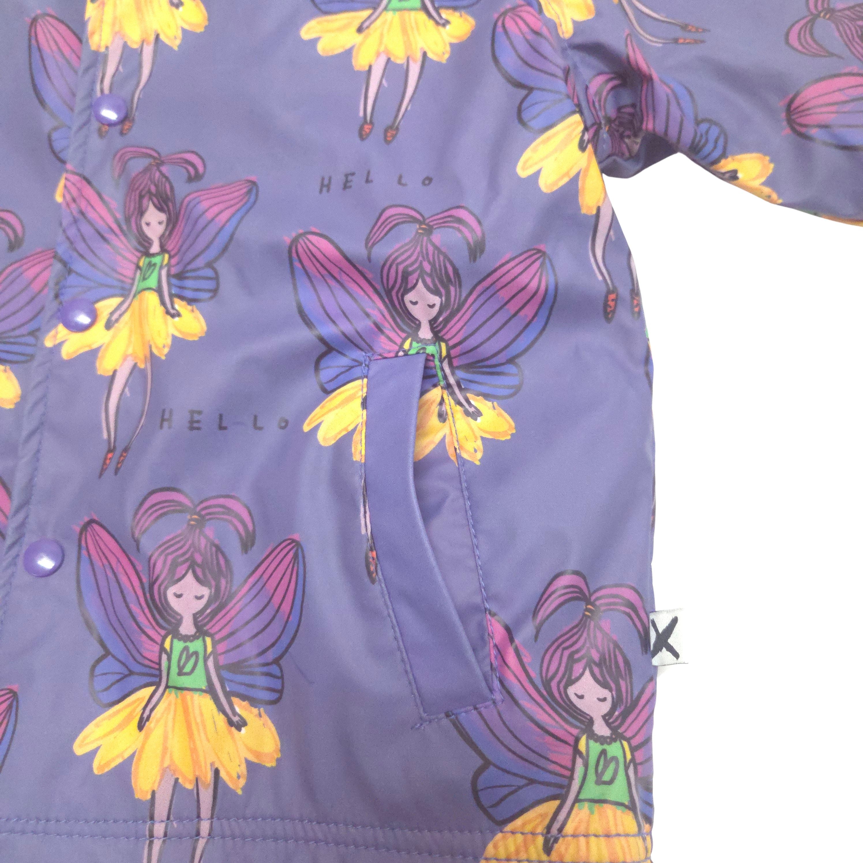 A close-up of a children's purple jacket or raincoat featuring a repeating print of cartoon fairy characters with yellow and pink wings, plus a front  pocket.