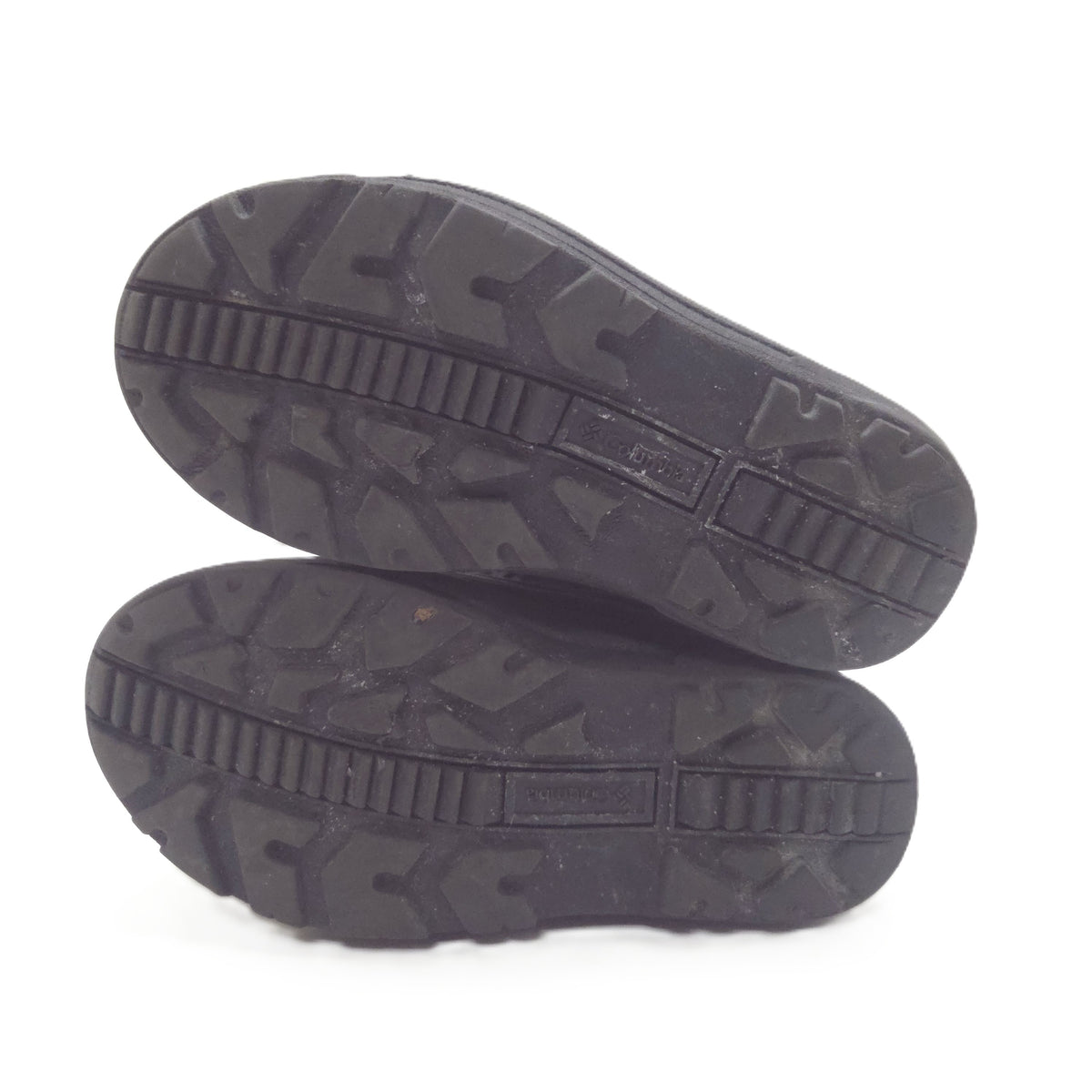 Two black rubber shoe soles shown from the bottom, displaying deep tread patterns and a textured outsole design, set against a plain white background.
