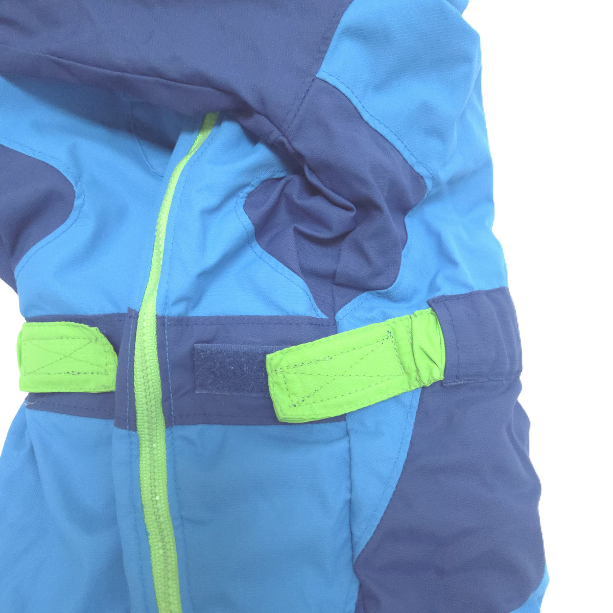 Close-up of a blue and navy winter jacket with bright neon green zipper and hook-and-loop strap details, shown on a white background.