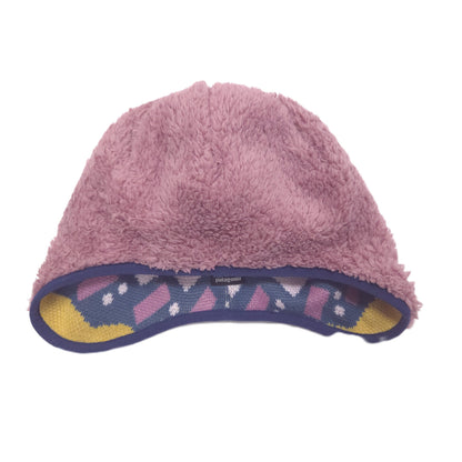 Reversible a pink fuzzy fleece beanie hat with a patterned knit brim trim in purple, pink, and yellow, shown against a plain white background.