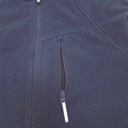 Close-up of a dark navy fleece jacket showing a zippered chest pocket with a reflective zipper pull.