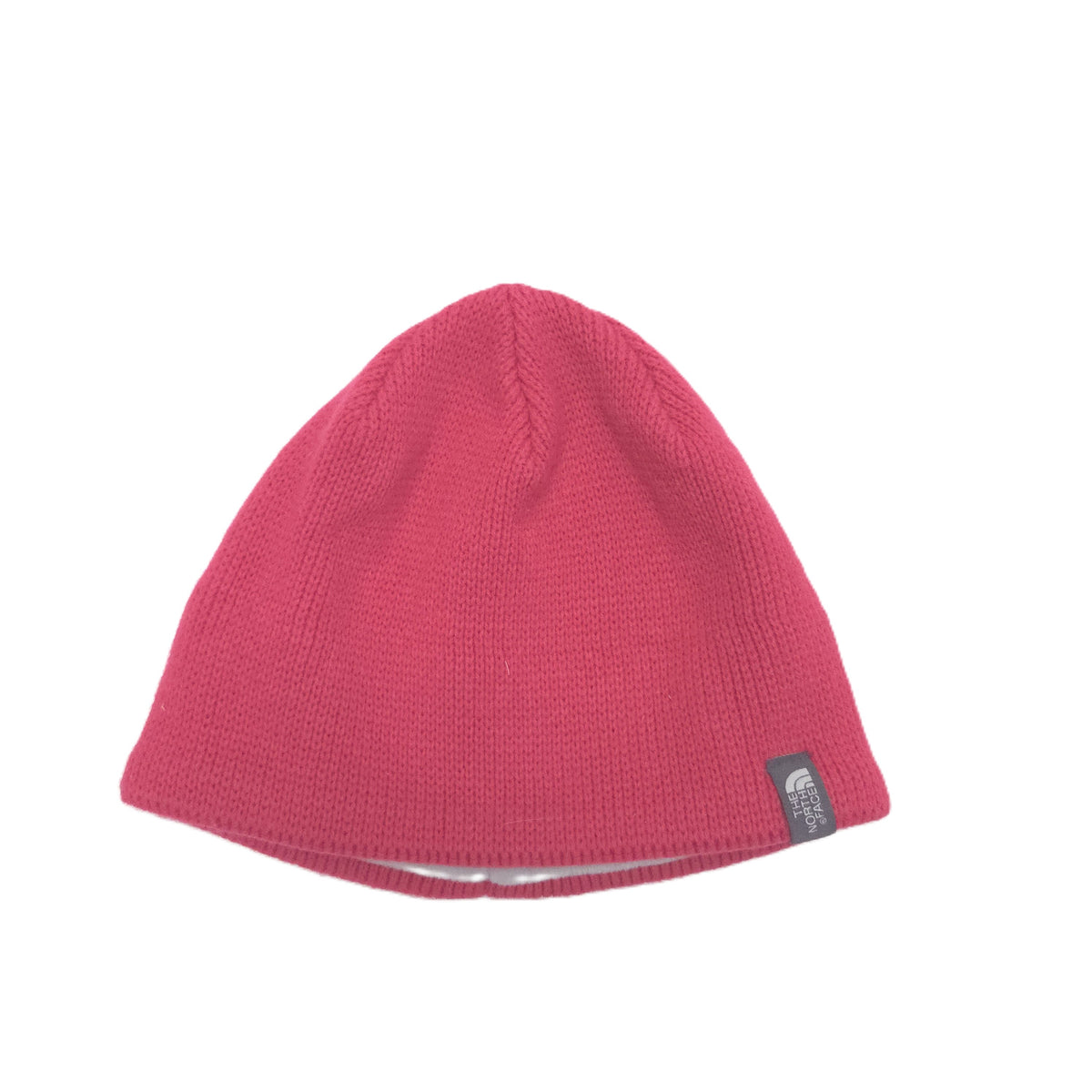 A pink ribbed knit beanie hat with a small black and white The North Face logo patch on the side, shown against a plain white background.