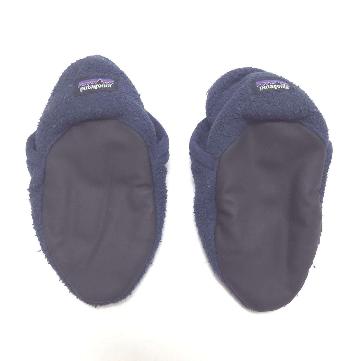 A pair of Patagonia fleece booties in navy blue, showing the fuzzy fleece exterior and dark gray synthetic footbeds against a white background.