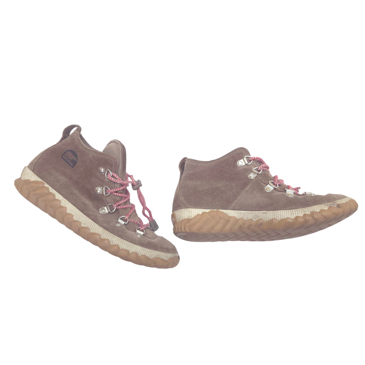 A pair of mid-height lace-up boots in brown suede with red laces and silver metal eyelets, featuring a thick tan and white wavy sole, shown against a plain white background.