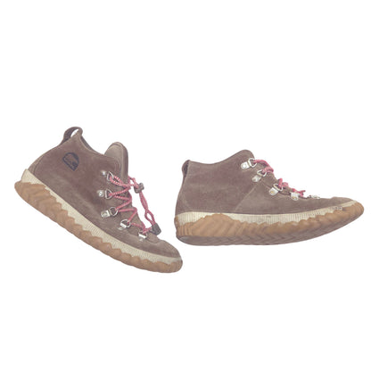 A pair of mid-height lace-up boots in brown suede with red laces and silver metal eyelets, featuring a thick tan and white wavy sole, shown against a plain white background.
