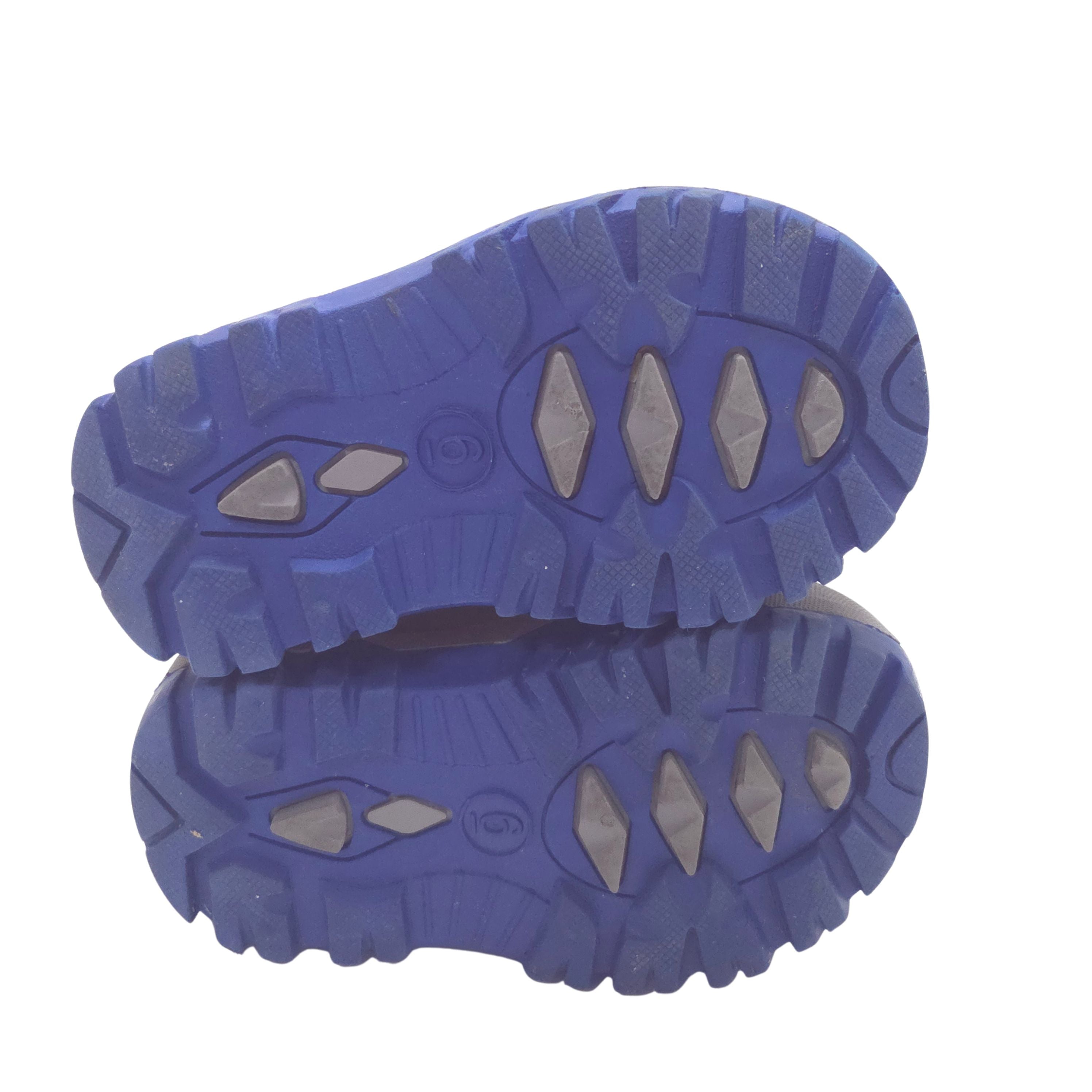 The outsole of a pair of blue winter shoes, showing the tread pattern, on a white background.