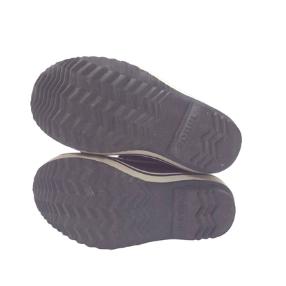 A pair of black slip-on shoes shown from the bottom, displaying their textured treaded soles against a plain white background.