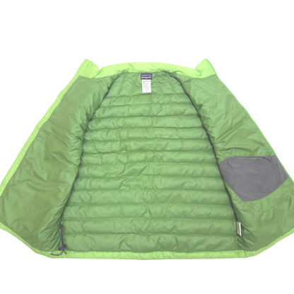 A green quilted puffer vest shown open against a white background, displaying its padded interior, a gray zippered pocket on the sleeve, and a Patagonia brand label at the collar.