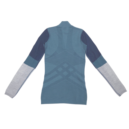 A women's long-sleeve athletic top shown from the back, featuring a high mock neck, a textured geometric diamond pattern in slate blue on the back, and color-blocked sleeves in navy and light gray.
