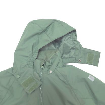 A close-up of a sage green hooded jacket with a front zipper, snap buttons, and hook-and-loop strap details on the hood and collar, shown against a plain white background.