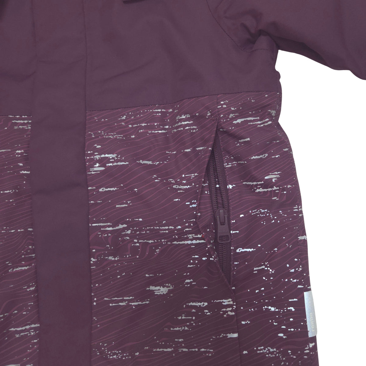 Close-up of a dark plum purple jacket with a textured, speckled patterned lower panel and a vertical zip pocket.