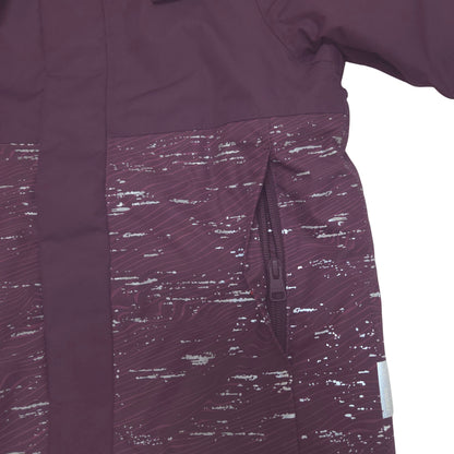 Close-up of a dark plum purple jacket with a textured, speckled patterned lower panel and a vertical zip pocket.