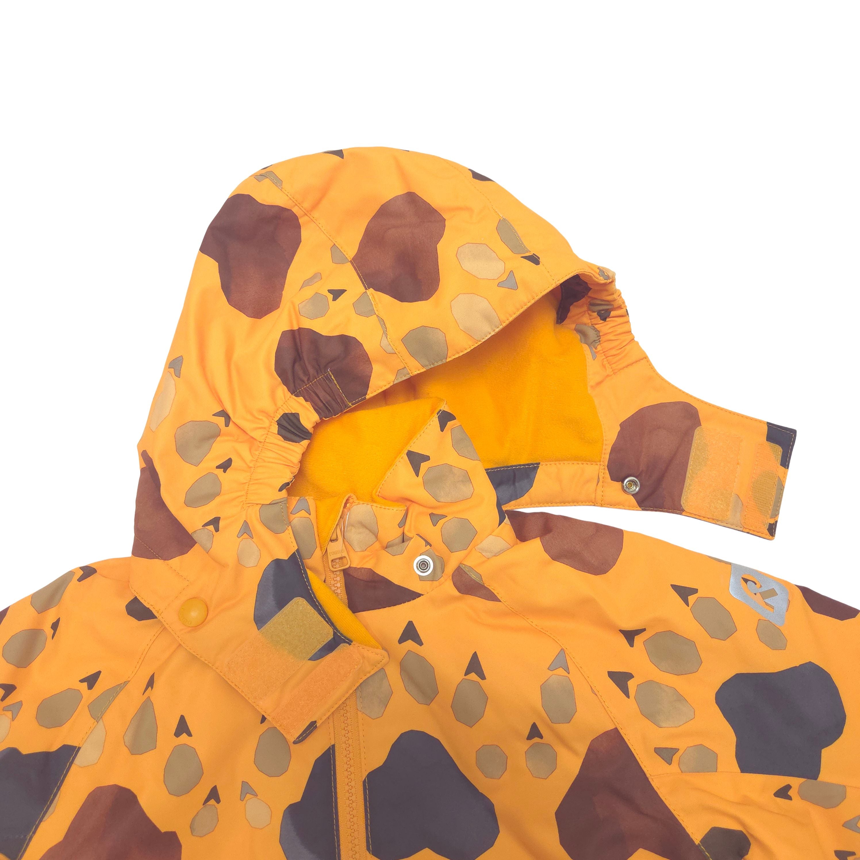 A close-up of a children's hooded winter jacket in a bright orange-yellow base color with a brown, gray, and beige animal footprint pattern, shown on a plain white background.