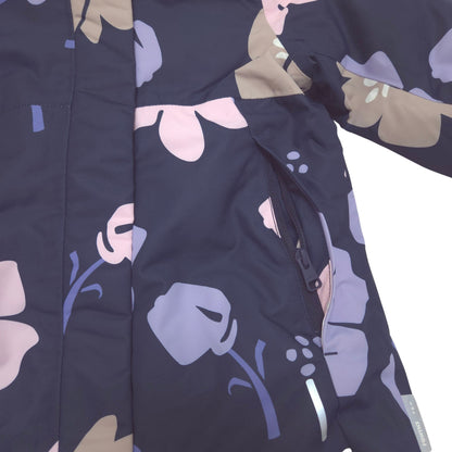 Close-up of a dark navy jacket with a floral pattern in lavender, light pink, and beige, featuring a zippered hand pocket.