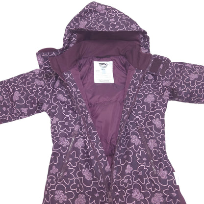 A purple hooded winter jacket with a white floral pattern, laid flat against a white background. The brand label 'reima' is visible inside the collar.