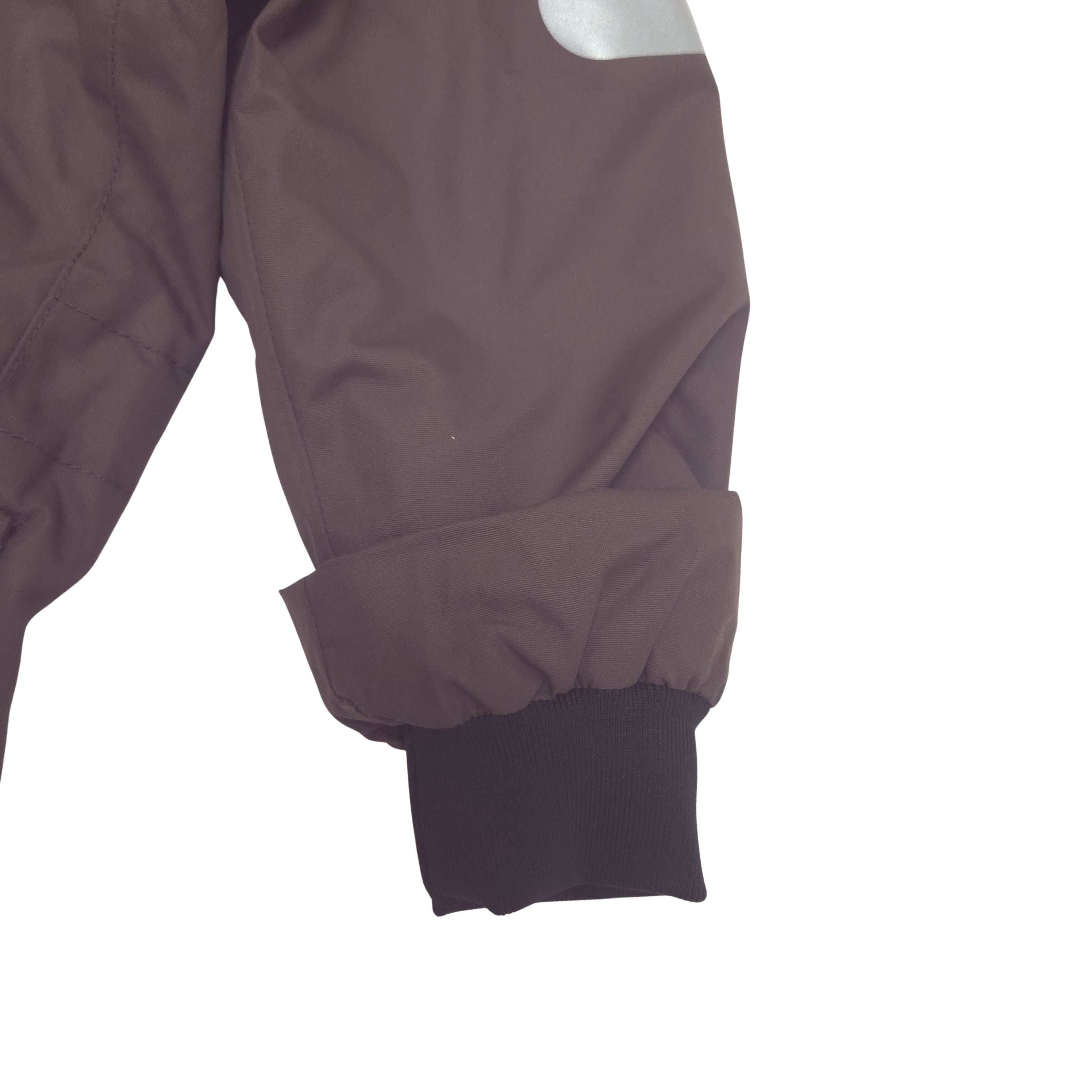 Close-up of a dark brown suit sleeve with a black ribbed cuff