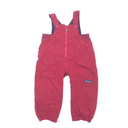 A pair of Patagonia children's snow pants in a red color, featuring a half-zip front, adjustable shoulder straps, and elastic cuffs, shown against a plain white background.