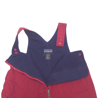 A Patagonia snow pants shown from the inside, featuring a navy blue fleece bib panel with a red zipper and red trim, and a red outer shell.
