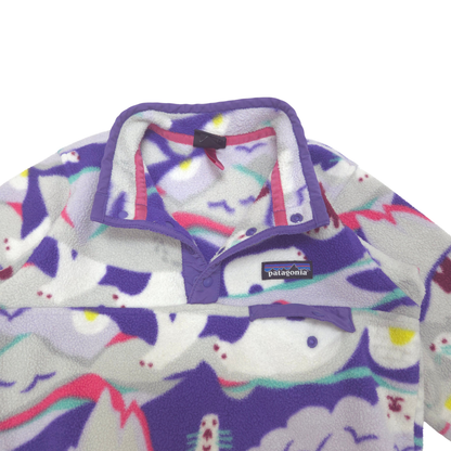 Close-up of a Patagonia fleece pullover with a purple collar and a multicolor abstract pattern on a white background. small chest pocket