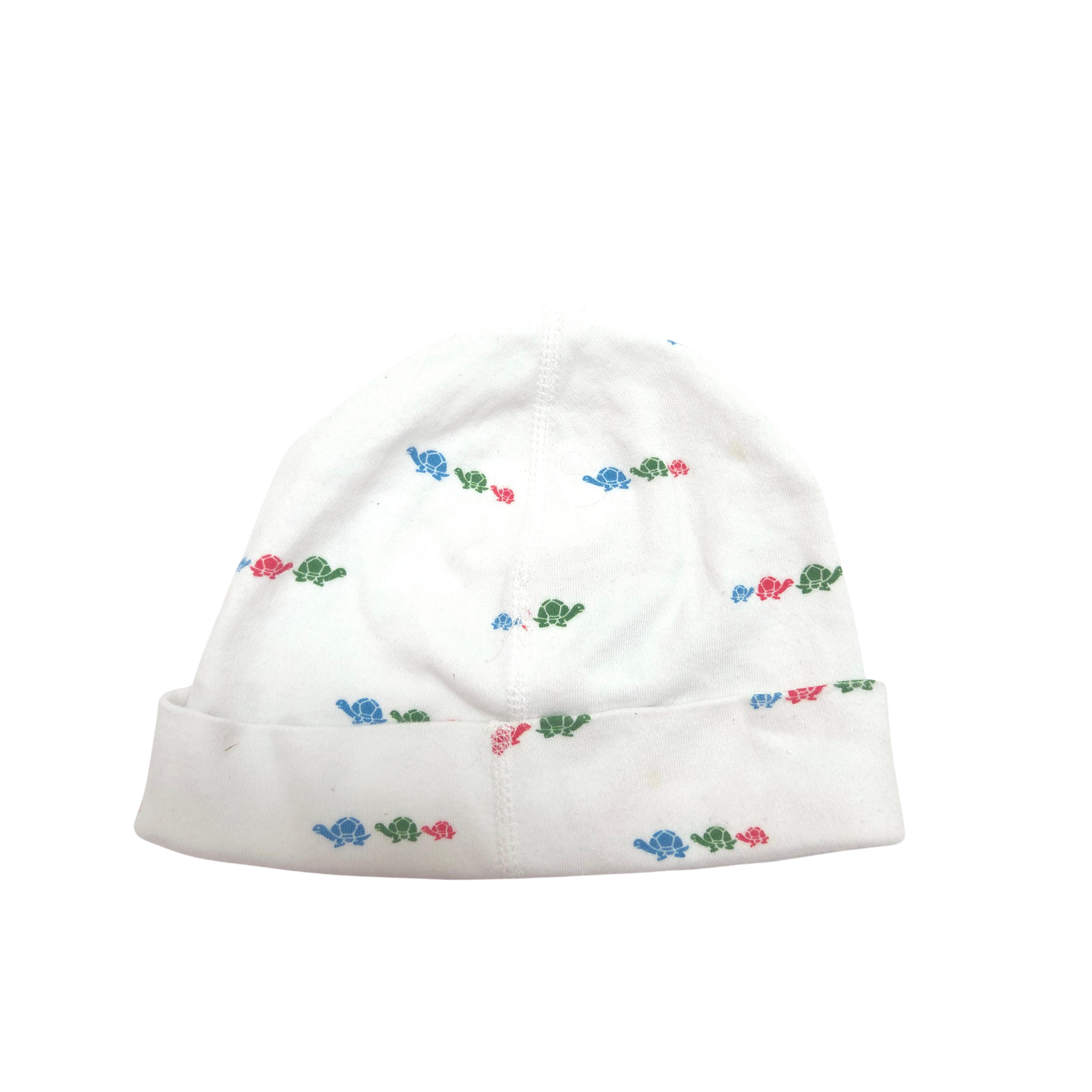 A white knit baby beanie hat with a small repeating pattern of colorful turtles in blue, red, and green, featuring a folded cuff.