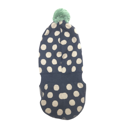 A balaclava with a fluffy pom-pom, featuring a black base with cream-colored polka dots, shown against a plain white background.