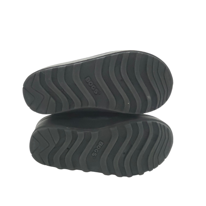 A pair of black boots shown from the sole view, featuring a wavy tread pattern and the BOOS brand name embossed on the rubber.