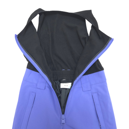 A close-up of a blue and black zippered bib snow pants, showing the interior, zipper track, and a small interior label.