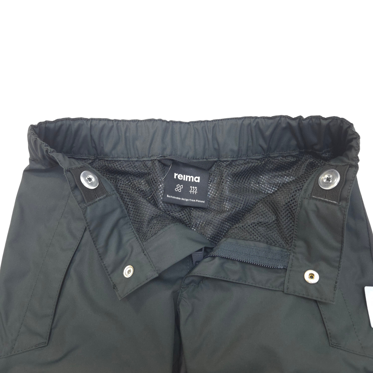 Close-up of the waistband and inner construction of black pants, showing a mesh lining, snap buttons, and a visible Reima brand label.