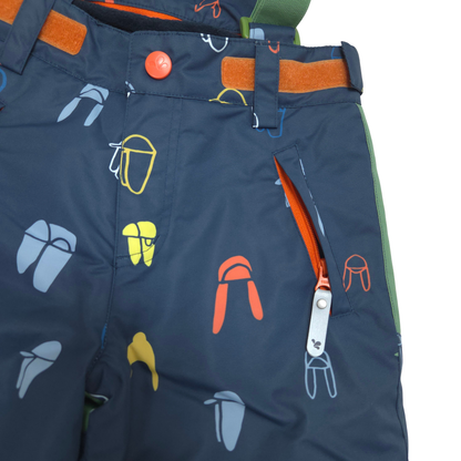 Close-up of dark navy children's snow pants with a colorful outdoor gear print, including orange, yellow, and light blue icons. Features a zippered pocket with an orange lining and a silver zipper pull.